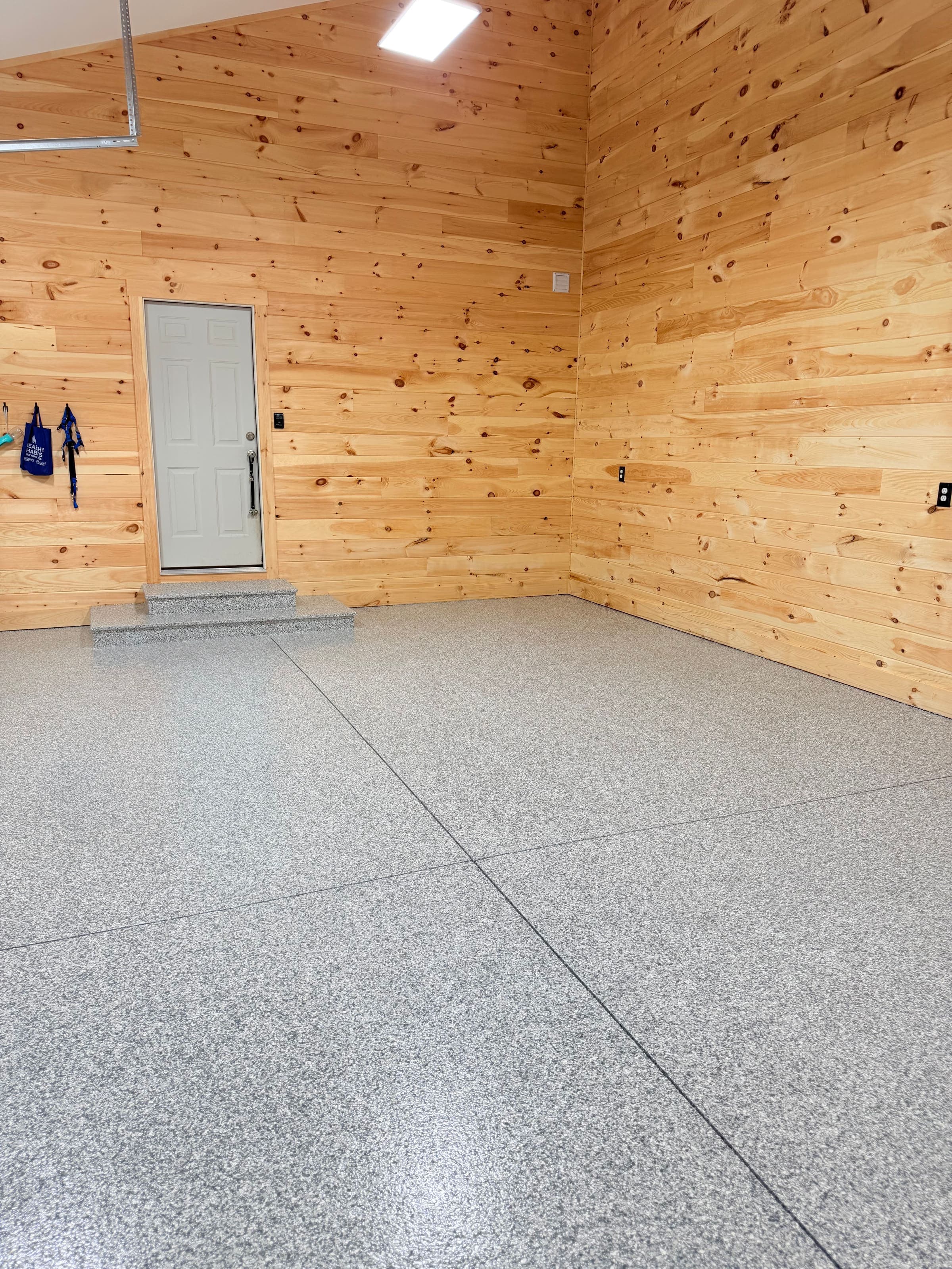 Camp garage corner with pine walls and a gray flake epoxy floor