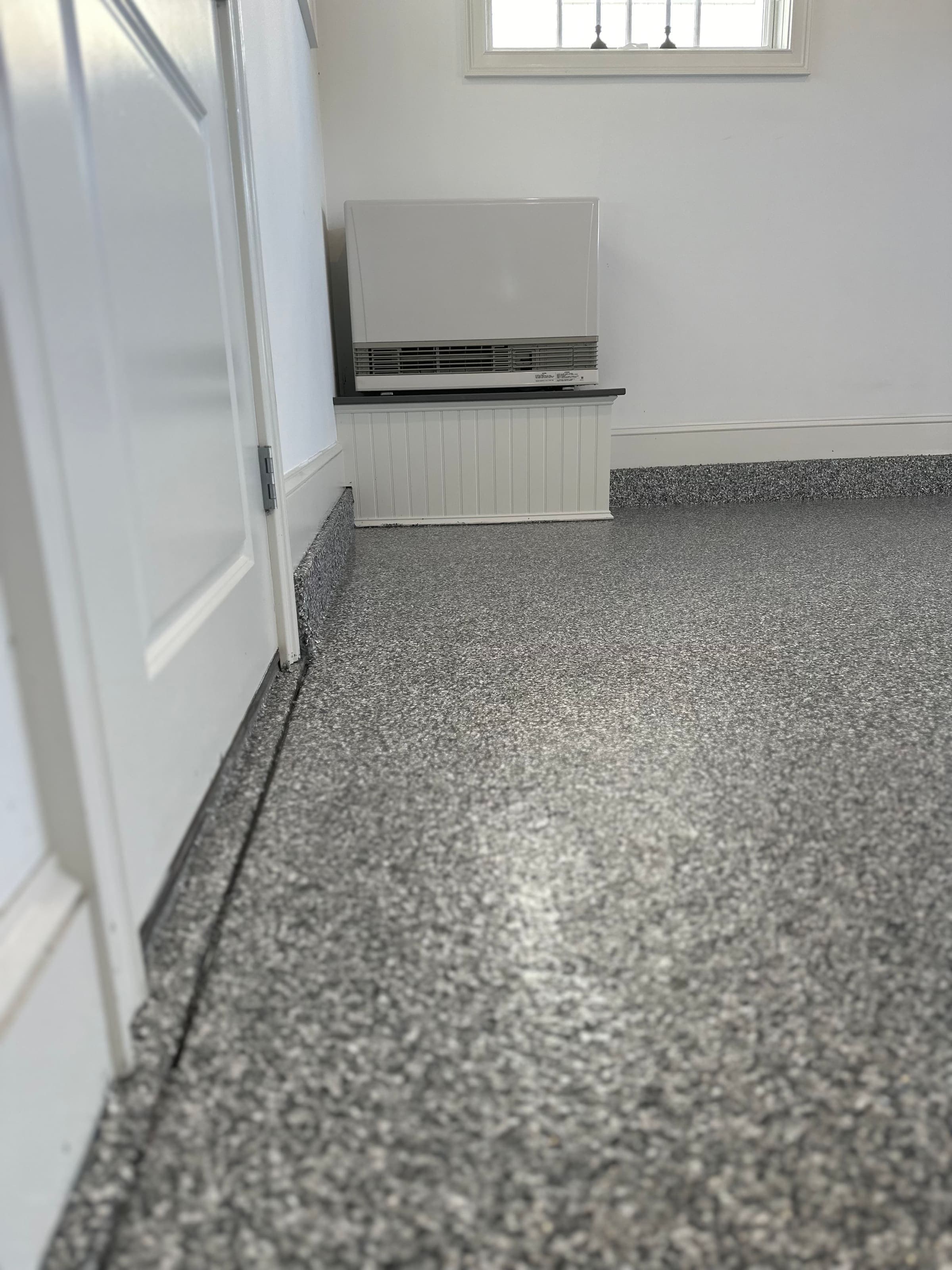 Finished basement with a light flake epoxy floor and white walls
