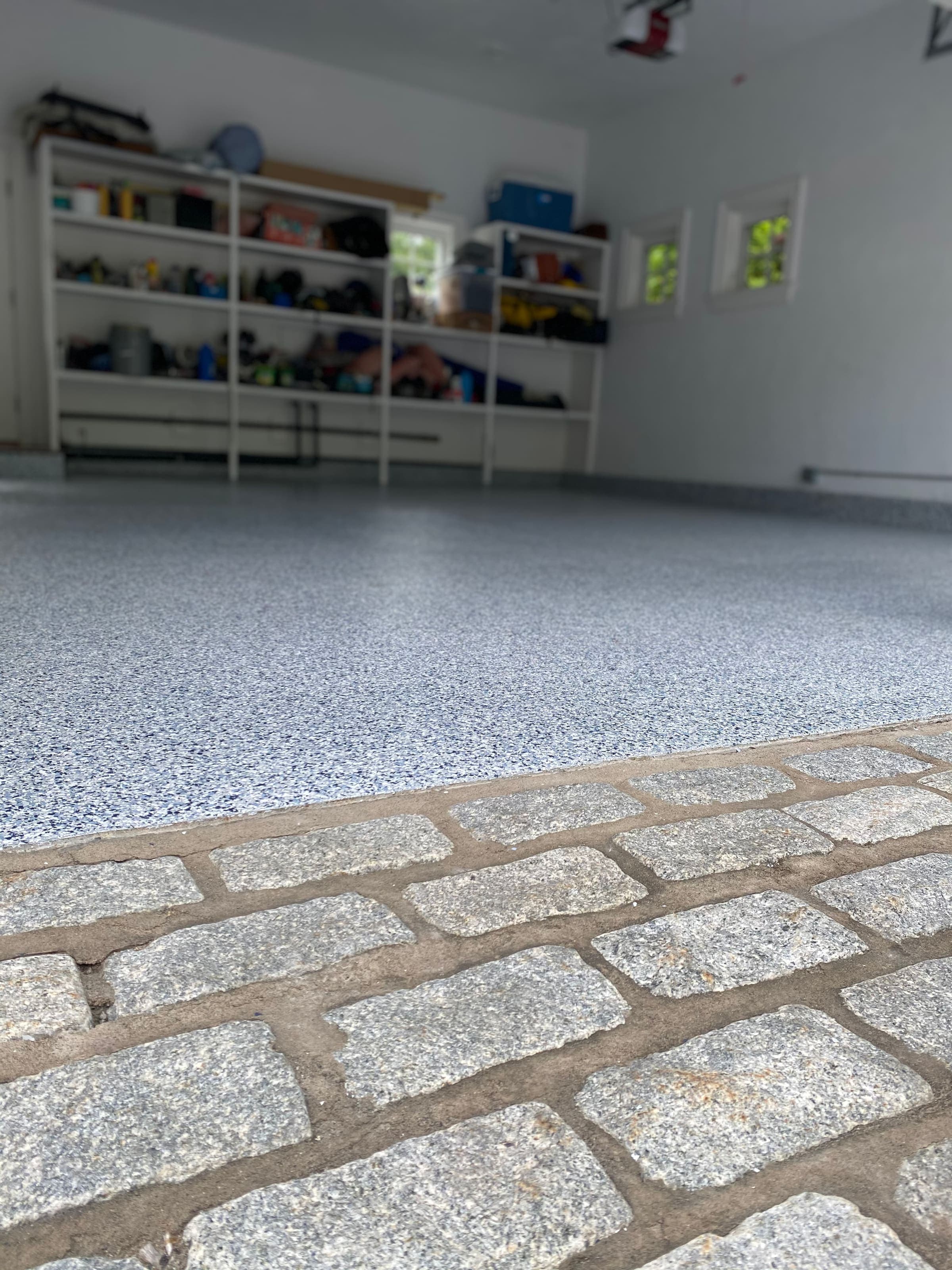Flake epoxy floor meeting a cobblestone garage apron