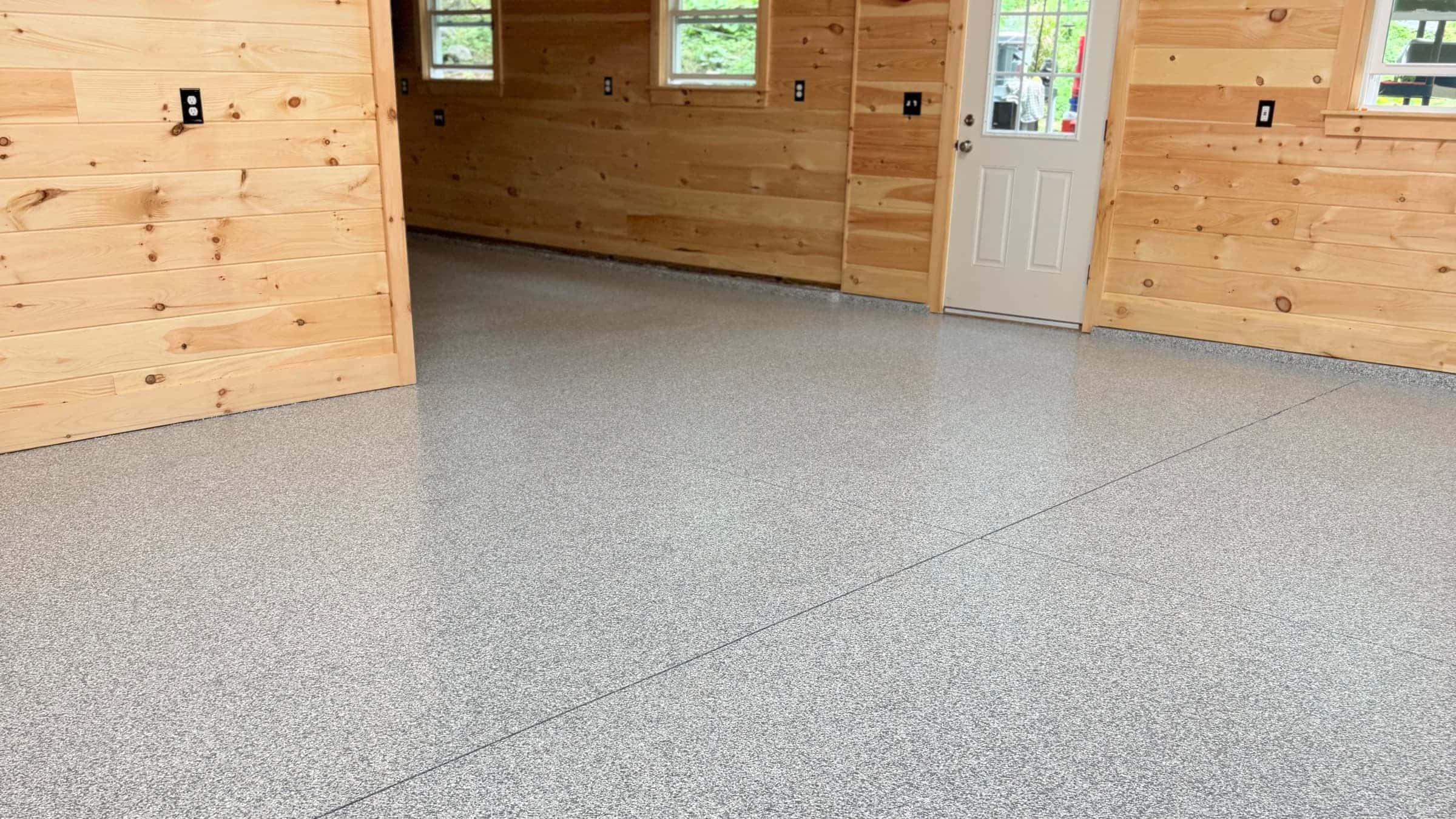 Lakeside camp garage in Casco, Maine with pine walls and a gray full-flake epoxy floor